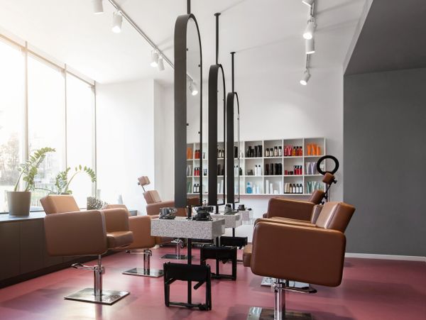 Modern hair salon with brown chairs and large mirrors.