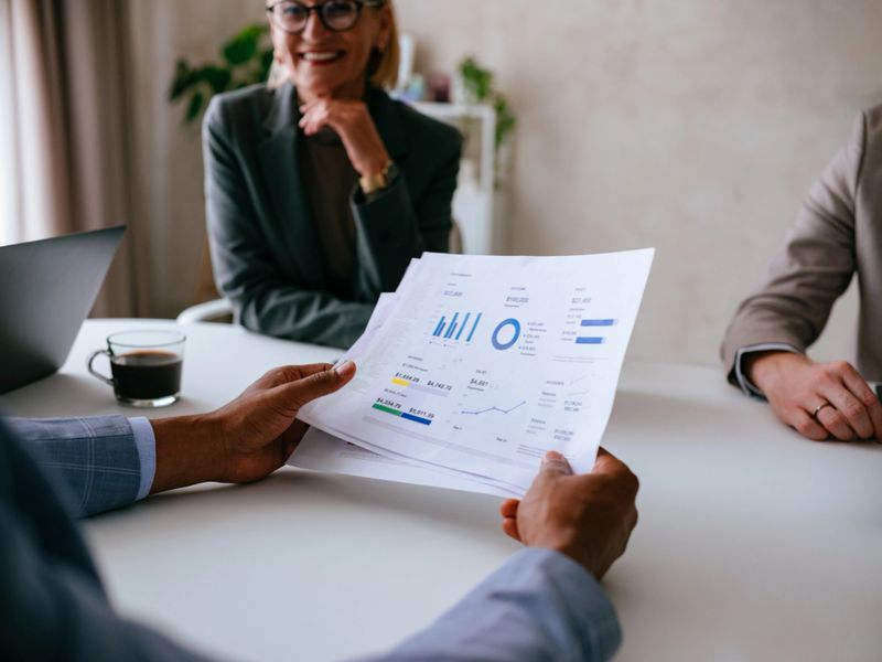 A professional group engaged in a business meeting, analyzing data charts and discussing financial strategies. Ideal for themes of teamwork, corporate planning, and decision-making.