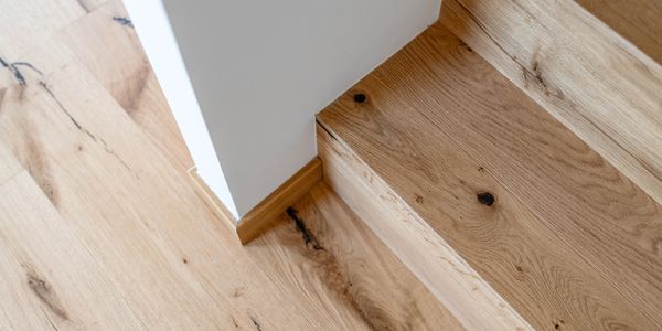 Close-up of wooden flooring and steps with a white wall corner.
