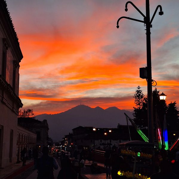 Sunset casting vibrant orange hues over a mountain and busy street scene.