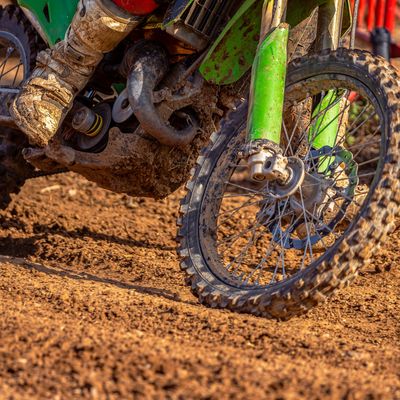 Close-up of muddy motocross bike wheels and rider's boots.