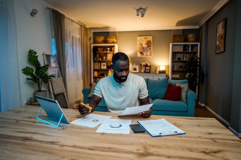 Young worried man manages finances at home at night