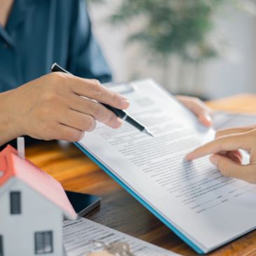 Two people reviewing a legal document with a model house on the table.