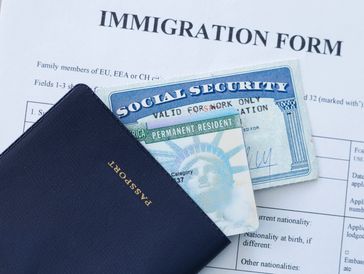 Passport, social security card, and permanent resident card on an immigration form.