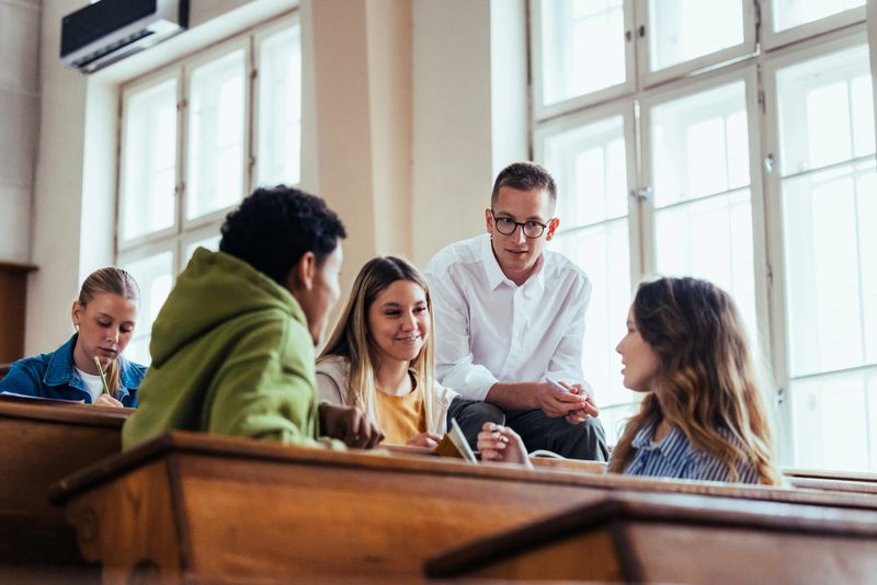 A diverse group of students engaged in animated discussion in a bright university classroom setting, demonstrating collaborative learning and educational engagement.
