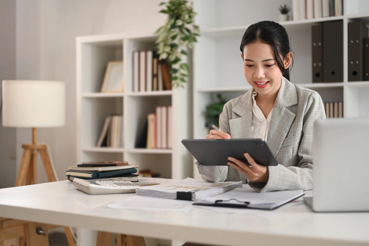 A woman working on a tablet at a desk in a modern office.