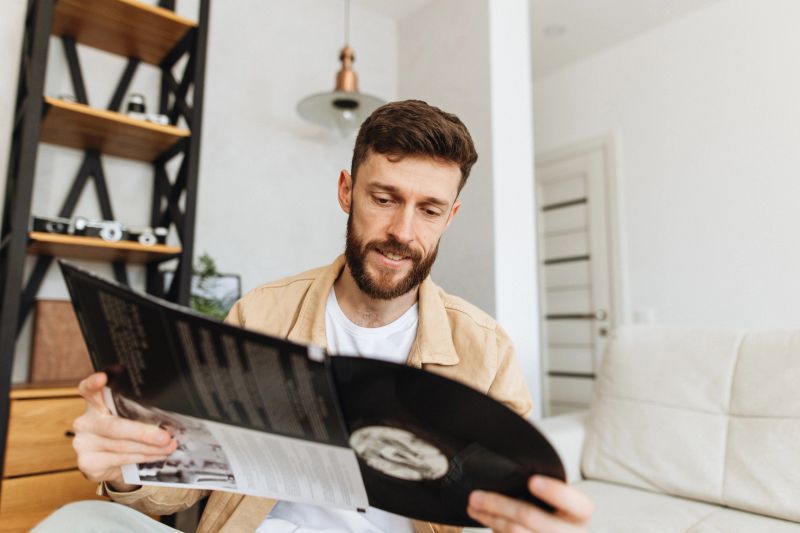 A handsome man is thoughtfully selecting a vinyl album from his home collection, preparing to enjoy some music