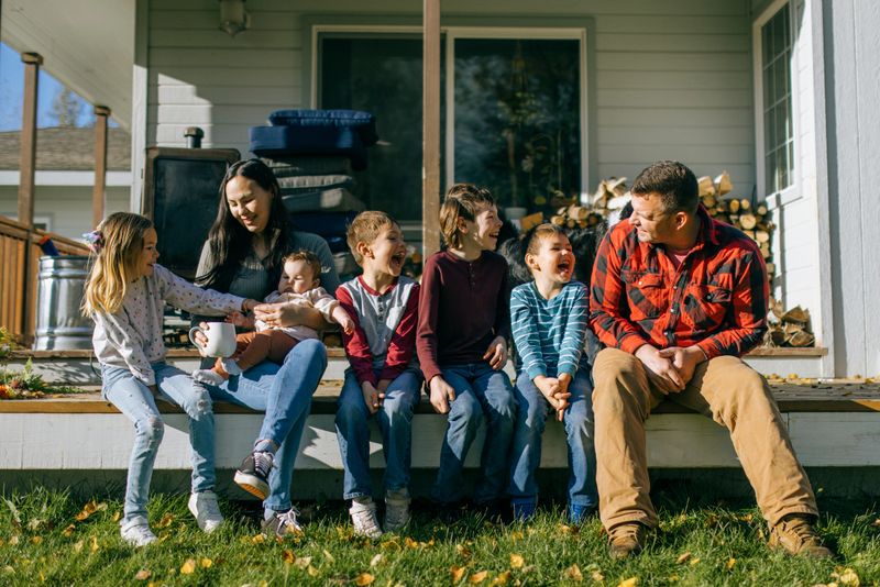 A young family, the father Caucasian and mother Indigenous North American, enjoy time together with their children at their house on a sunny day.  Shot near Palmer Alaska.