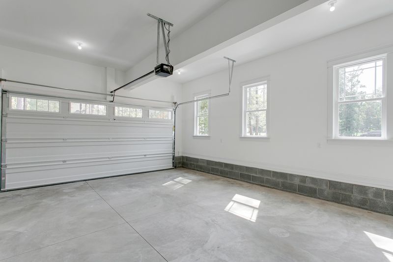 This image depicts a clean, bright garage with dual overhead doors half open, providing an inviting space with ample natural light filtering through the windows.