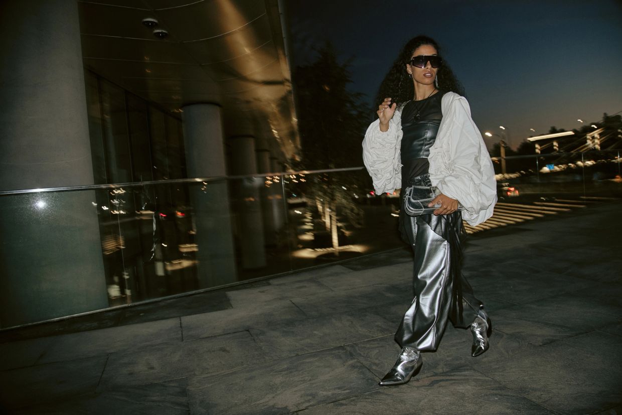 Fashionable woman walking at night in metallic and white outfit.