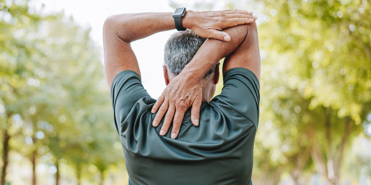 Man stretching his arm behind his head outdoors.