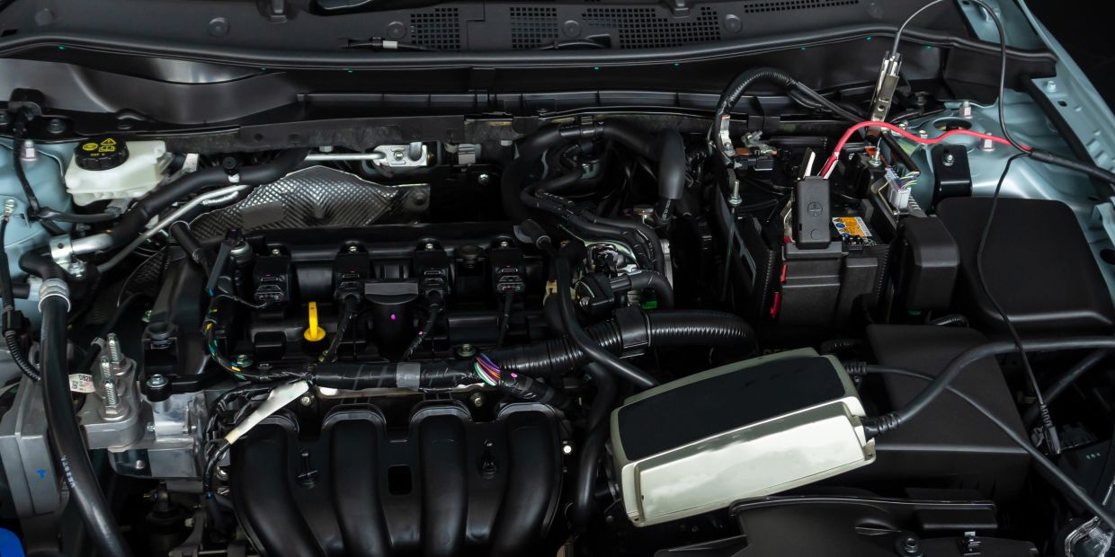 Car engine bay with diagnostic equipment connected.