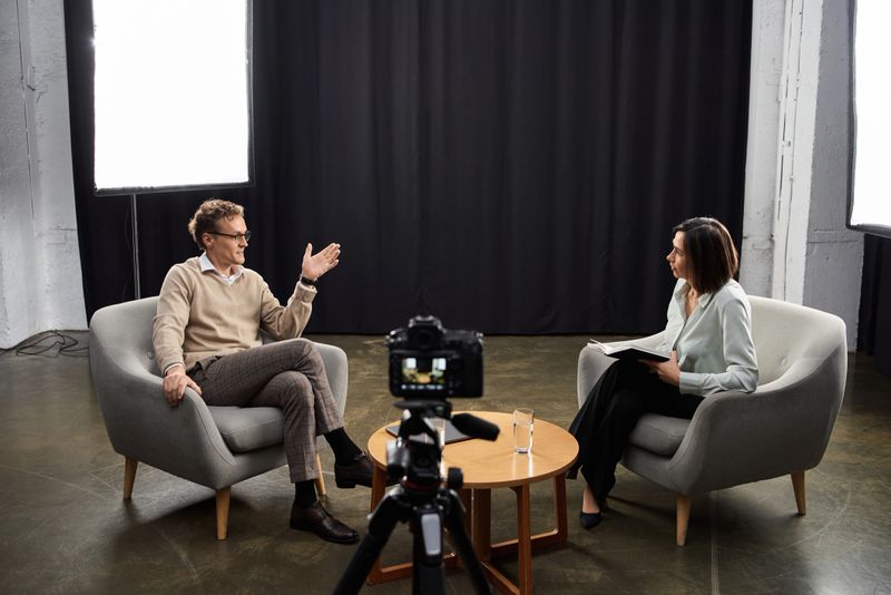 A journalist conducts a lively interview with a guest in a well-lit studio, fostering insightful discussion.