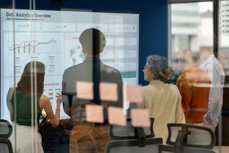 Diverse business development team brainstorming new products and services using a digital display during a business meeting. Business Intelligence and data-driven decisions empowering strategy, growth, and resilience in a modern office. Collaboration and innovation in action.