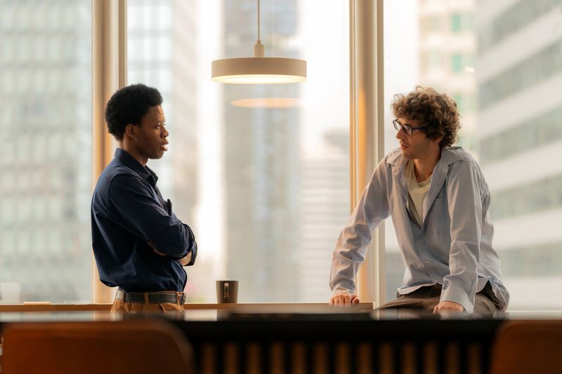 Two business professionals discussing project plans over coffee in a modern office at dusk. The warm glow of sunset enhances the focus on digital transformation, strategy, and growth in a corporate setting, with a view toward innovation and forward-thinking solutions.