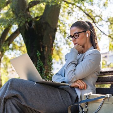 Woman working on laptop in park.