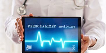 Doctor holding a tablet showing 'PERSONALIZED medicine' with a heartbeat line.