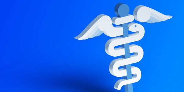 Stethoscope and medical icons on wooden blocks forming a cross on a blue background.