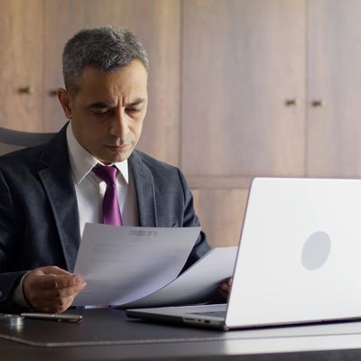 Man in suit reviewing documents at a desk.