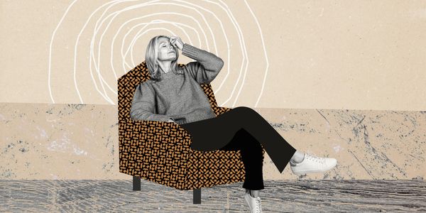 A woman relaxes in a patterned armchair with a contemplative expression.