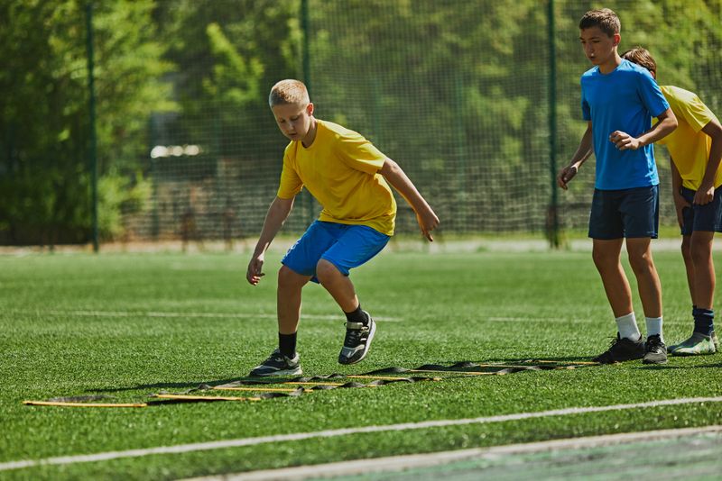 Focused Footwork Training. : Children in uniform training outdoors on soccer field, performing fast-paced agility drills . Concept of sport, school, childhood, hobby, active lifestyle