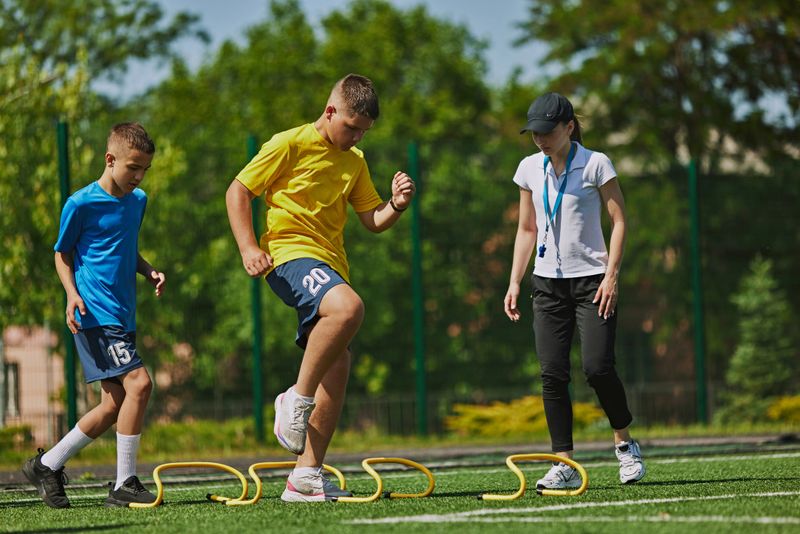 Teamwork and Strategy. Kids in sportswear training with female coach on outdoor soccer field. Teamwork and strategic play Concept of sport, school, childhood, hobby, active lifestyle