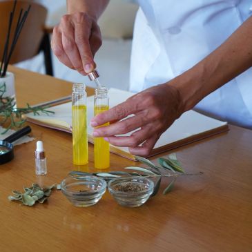Person using a dropper to mix yellow liquid in glass bottles.