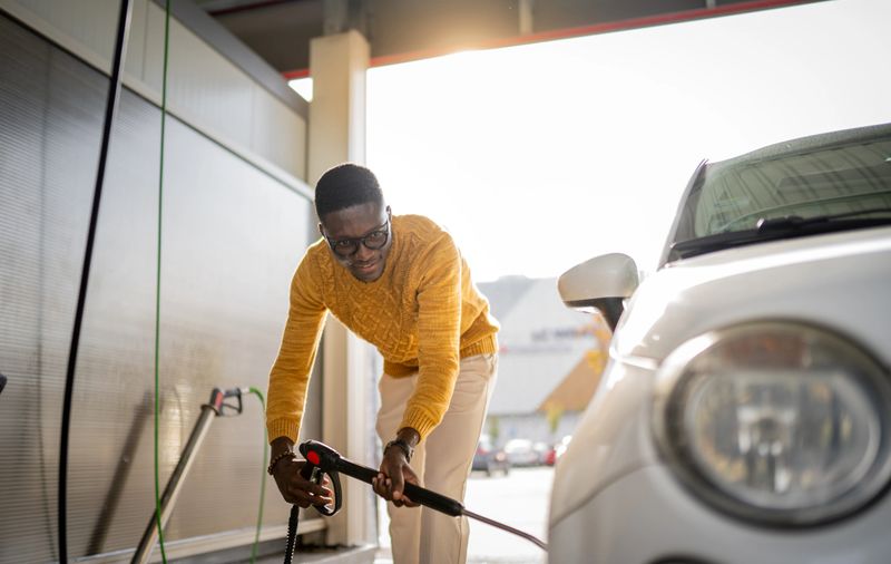 Young African man washing his car in a self service car wash