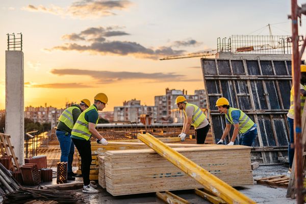 Group of workers moving lumber on a site at sunset.