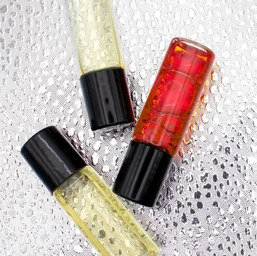 Three small perfume or essential oil bottles on a textured silver surface.