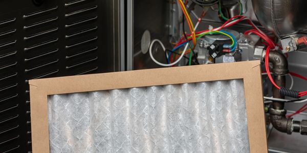 A new air filter is positioned in front of a furnace's internal components.