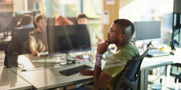 Man thoughtfully working at computer in office.