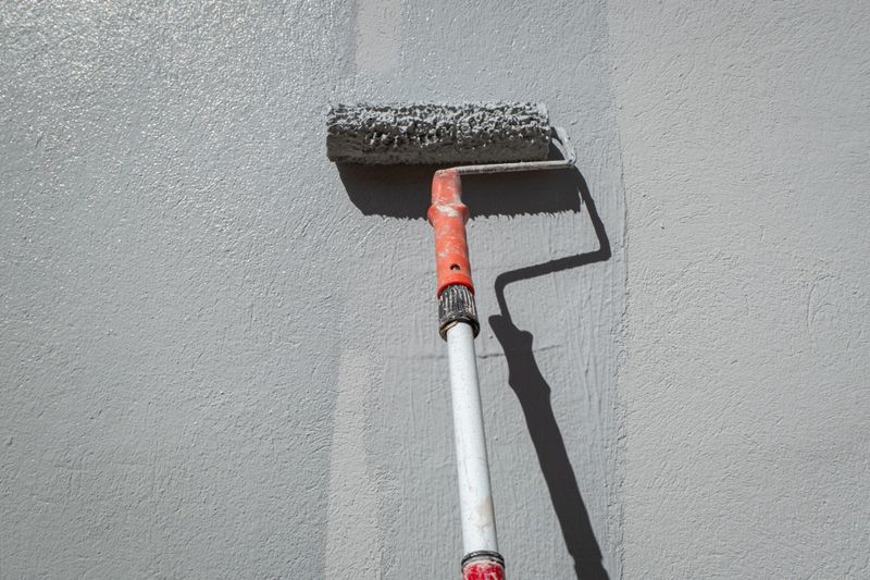 The painter with his roller on the painter's stick painting the wall