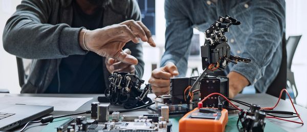 Two people working with robotic hands and electronics.