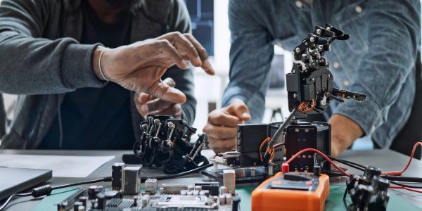 People working on robotic hands and electronics.