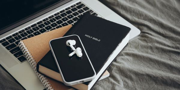 Bible, phone, and earphones on laptop.