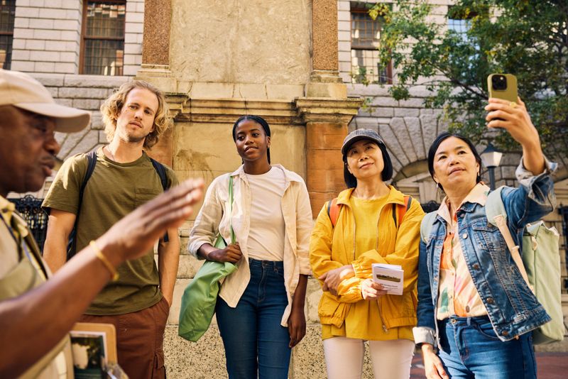 Diverse group of tourists on a city tour with guide. Outdoor urban setting with people listening to a guide. Travel and exploration concept.