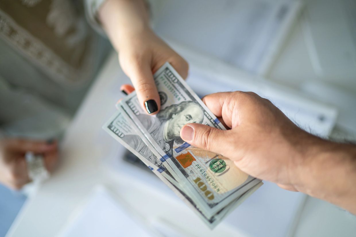 Hands exchanging hundred dollar bills.