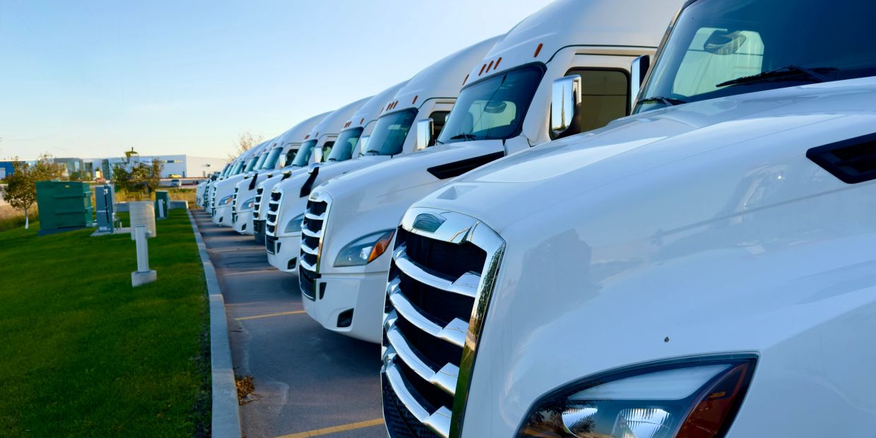 Row of white semi-trucks parked in a line.