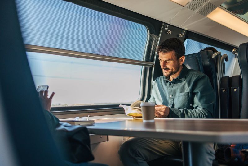 A mid-adult, cheerful, handsome man traveling by train.