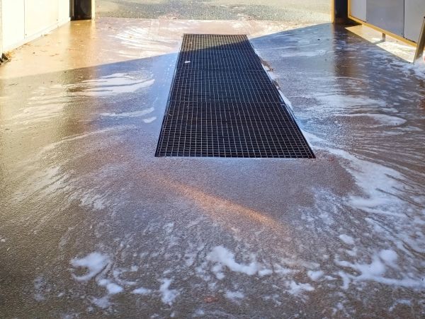 Wet floor with soap suds and drainage grate.