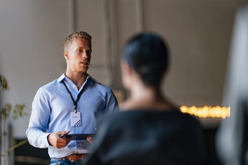 Professional speaker delivering a lecture at a business conference, engaging the audience with insightful dialogue. The setting conveys a sense of collaboration and knowledge-sharing among peers.