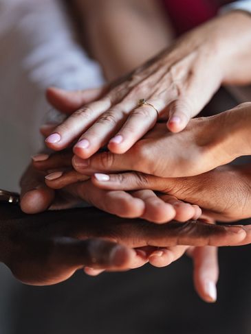 Diverse hands stacked together symbolizing unity and teamwork.