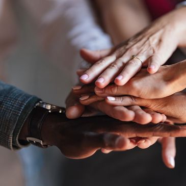 Diverse hands stacked together symbolizing unity and support.