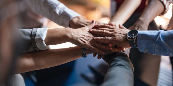 Multiple hands stacked, symbolizing teamwork and unity.