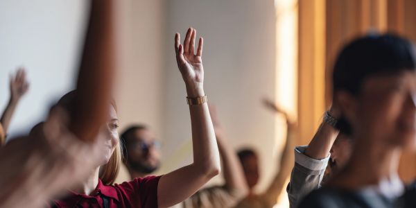 People raising hands in a group setting.