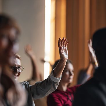 People raising their hands in a meeting.