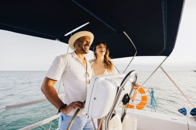 A happy couple enjoying sailing on a boat under a clear sky.