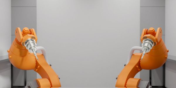 Two orange industrial robotic arms facing each other in a clean, minimalistic workspace.