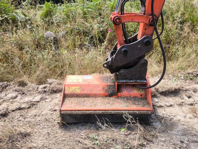 Orange excavator attachment clearing land.